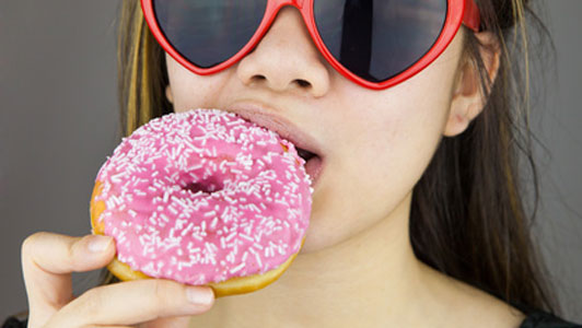 women in red heart shaped glasses eating pink donut