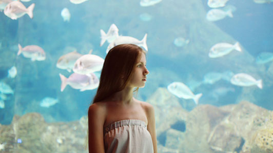 woman standing in front of aquarium alone