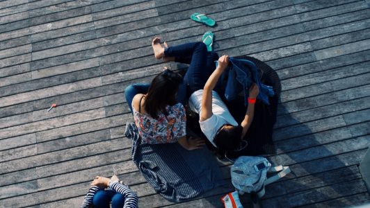 Guy lying in the sun with his back turned away from a girl.