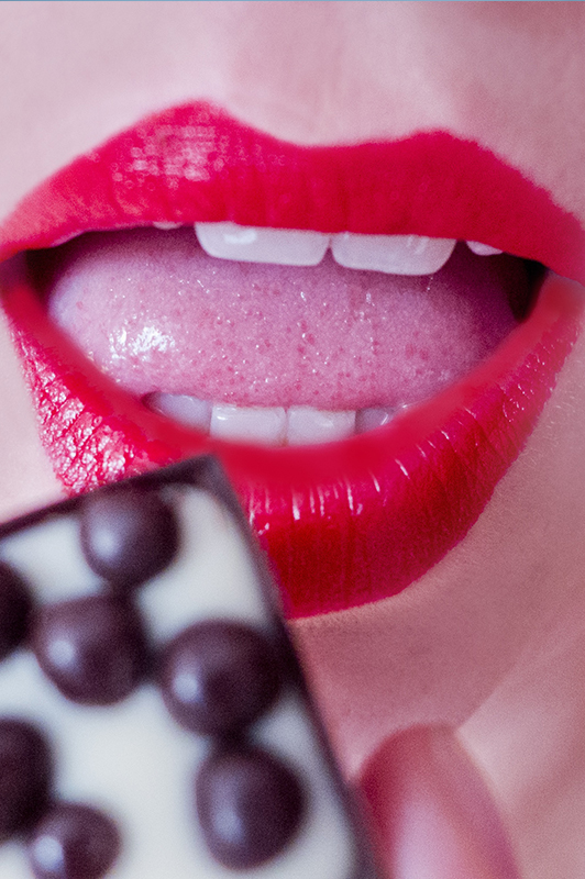 Girl with red lips eating chocolate.