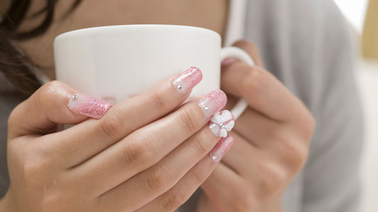 women with nails done holding coffee cup