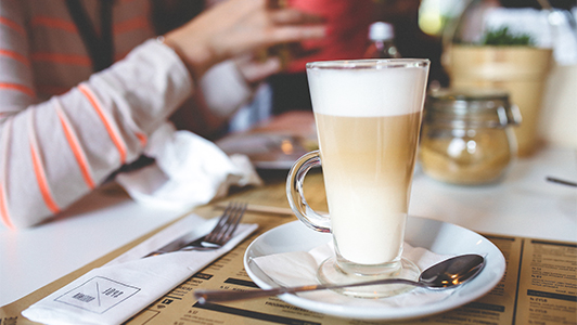 A cup of latte and someone's arm.