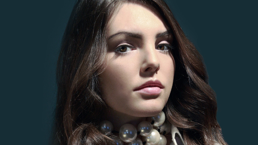 Girl with long brown hair and huge pearl necklace.