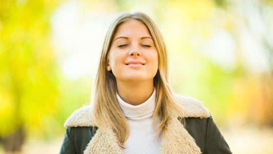 happy woman with eyes closed breathing fresh air outdoors