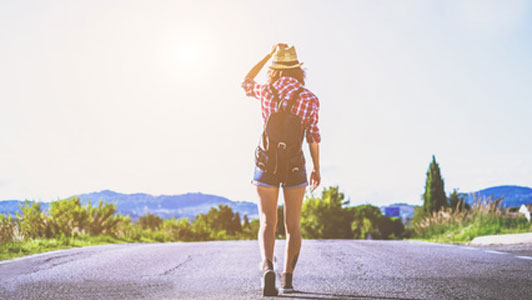 woman in strawhat walking down road