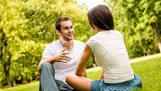 guy and girl sitting down together talking outside