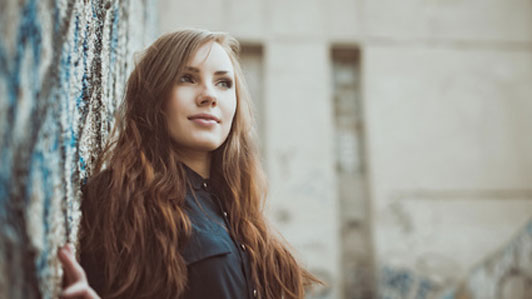 self-assured woman standing against wall