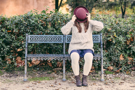 woman hiding behind hat