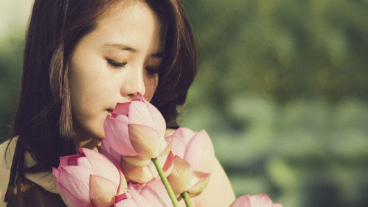 Girl smelling pink tulips.