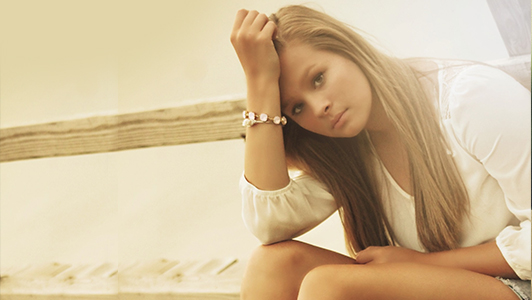 Girl in a white blouse leaning her head on he arm.