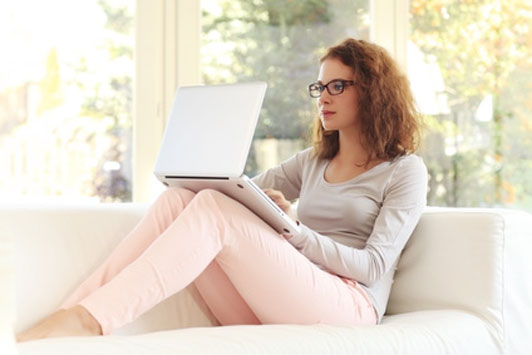 girl sitting on couch wearing glasses looking something up