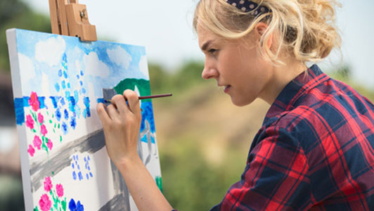 woman painting on canvas outdoors