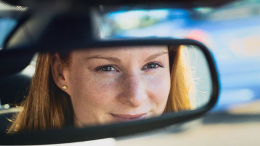 rear view mirror reflection of woman smiling in car