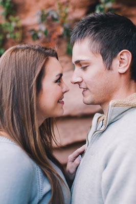 A brunette girl looking at a guy in a gray sweater with a zipper.