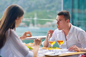 man with mouth full intently listening to woman 