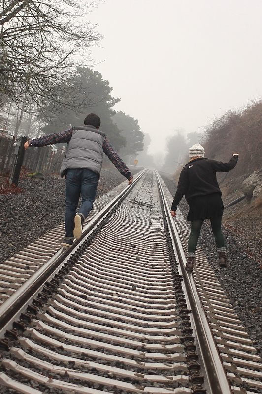 A couple acting foolish on a railway.