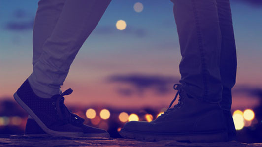 lights shining beyond shoes of couple on date