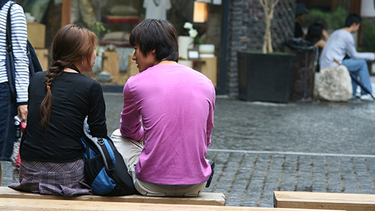 A couple sitting on a bench outdoors.