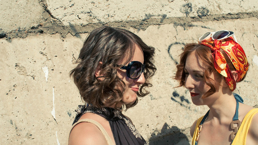 Two girls with short curly hair smiling.