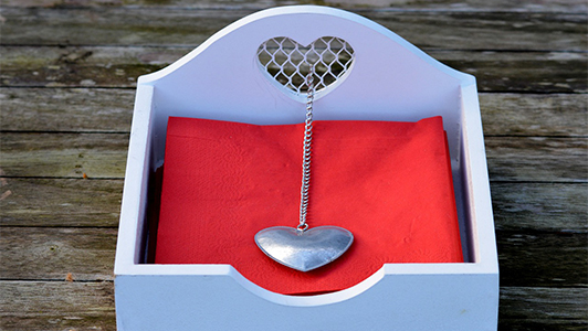 Red napkins in a box with a silver heart on a chain