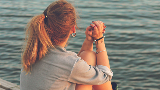 Girl with ginger pony tail looking at a river