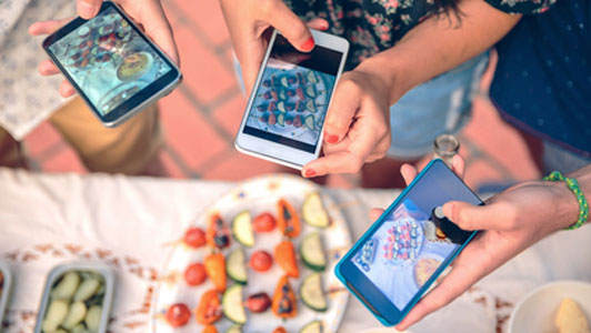 young people taking pictures of barbecue food at social gathering