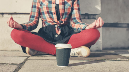 woman meditating in front of cup in street