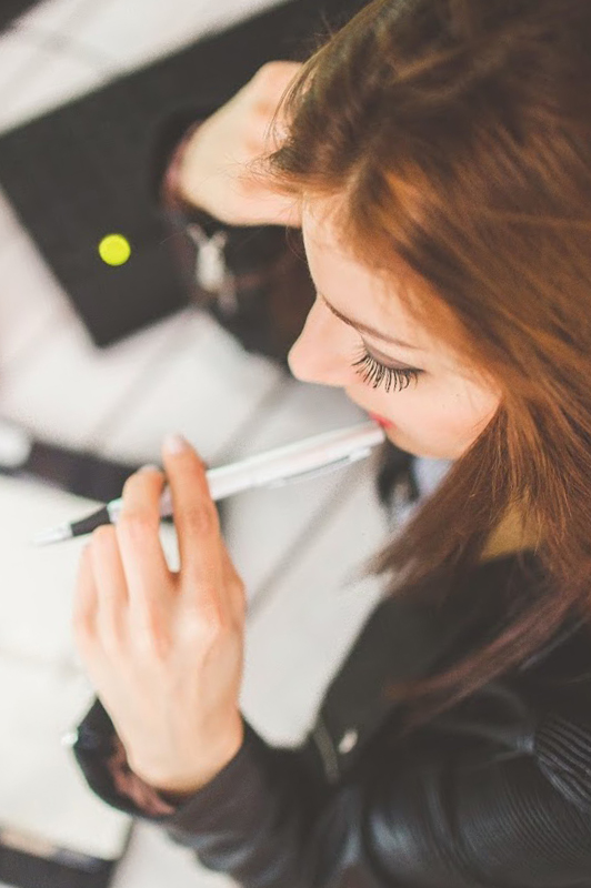 girl with pen in mouth thinking