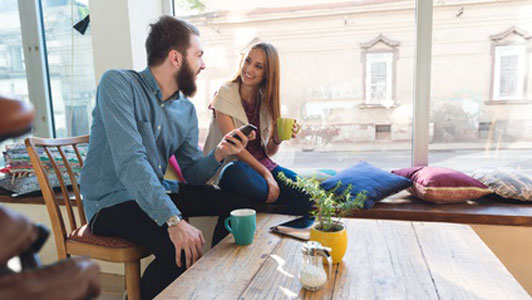 woman taking with guy holding phone over coffee