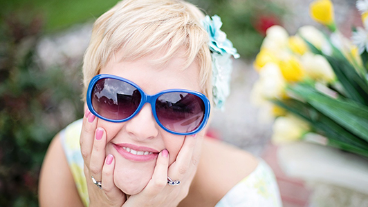 Girl with short hair and blue sunglasses resting her head on her hands.