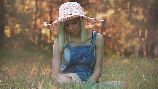 Girl in overals with a light pink hat on her head