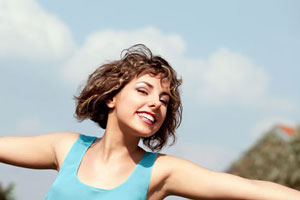 young woman in blue tank top arms wide open on clear day 