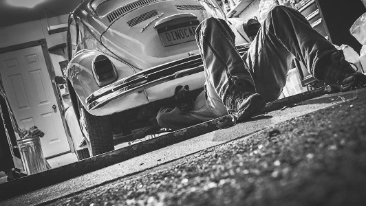 Guy lying under a car and repairing it.