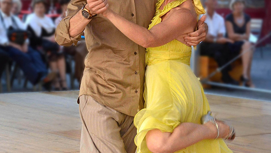 Girl in yellow dress dancing with a guy in a shirt.