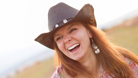 Girl with a cowboy hat grining widely.