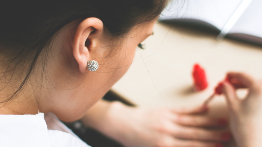 Girl painting her nails red.