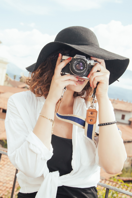 Girl with a hat holding a camera.