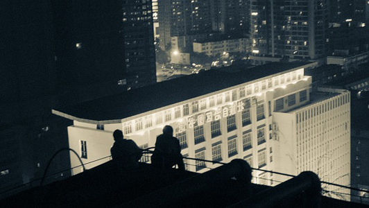 Two people sitting on the top of a building.