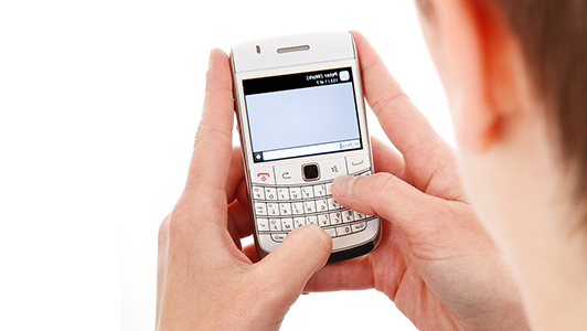 A person texting on a white blackberry phone