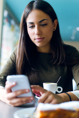 young woman in cafe sending invite on phone