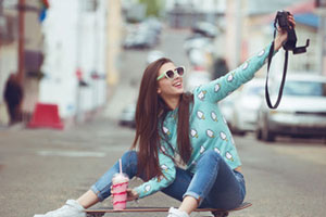 woman in blue clothes on skateboard taking selfie