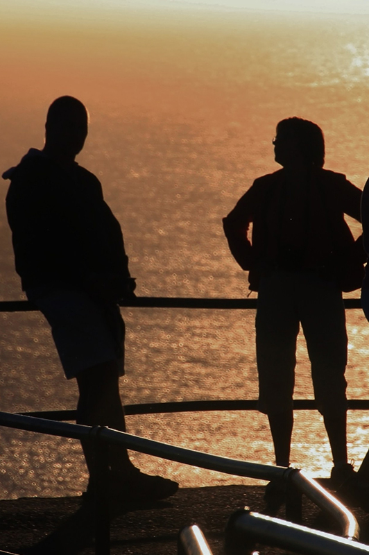 Two people standing on a deck in sunset