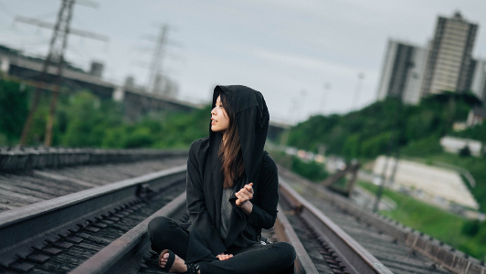young woman sitting in middle of track