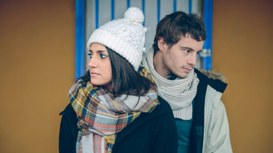 woman in hat standing with man behind her