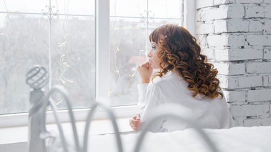 woman thinking in white room looking out window