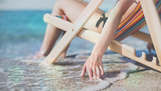 woman lying down on bench tanning at beach