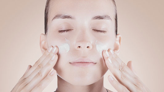 woman applying cream on face