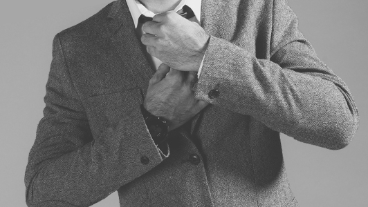 A man in a suit adjusting his tie.