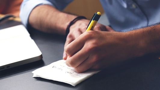 Guy writing something down with a yellow pen.