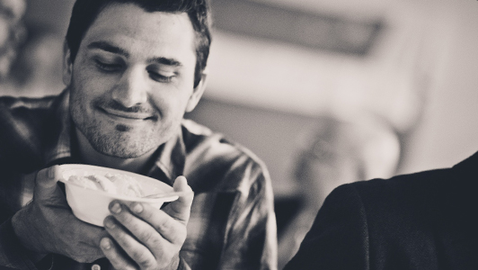 Guy smiling while holding a bowl in his hands.